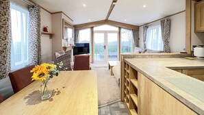 Un'ampia cucina con isola centrale, un'area pranzo con tavolo e sedie, e un televisore sullo sfondo.