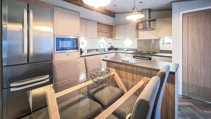 Une cuisine moderne dotée d’appareils électroménagers en acier inoxydable, de meubles en bois et d’un îlot central avec des sièges.