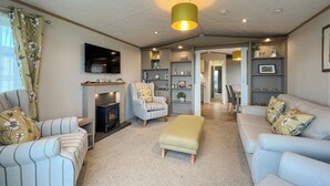 A living room with a fireplace, striped armchairs, a sofa, and a television. - 2 bedroom accommodation in St Andrews (St Andrews)