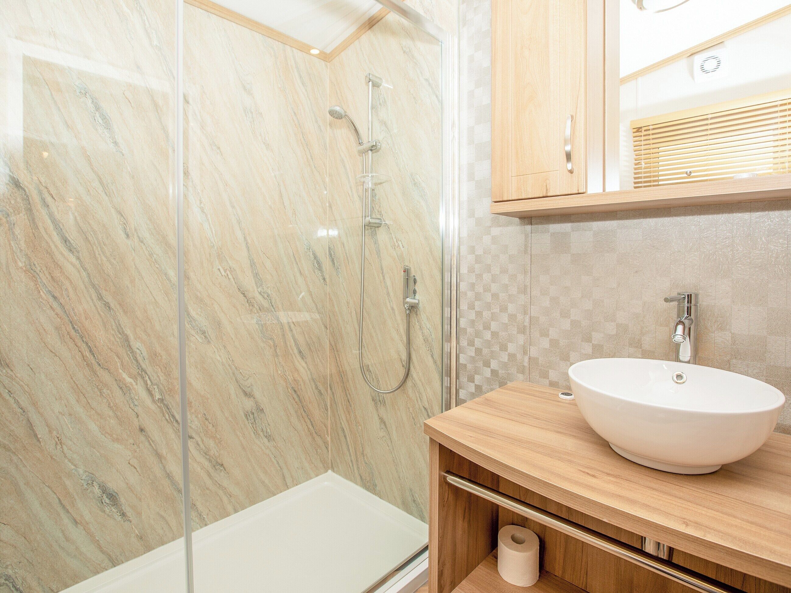 A modern bathroom with a glass-enclosed shower, a wooden vanity with a sink, and a toilet.