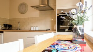 Een moderne keuken met witte kasten, een houten aanrecht en een bloemenvaas op de tafel.