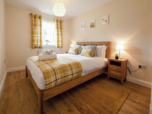 Une chambre à coucher avec un lit en bois, une table de chevet avec une lampe et une fenêtre avec des rideaux.