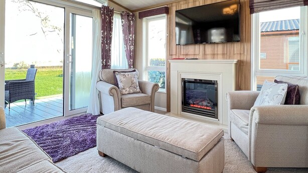 Ein gemütliches Wohnzimmer mit Kamin, bequemen Sitzgelegenheiten und einem Fernseher.
