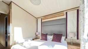 Ein Hotelzimmer mit einem großen Bett, einem Holzkopfteil, einem Nachttisch und einem Spiegel.