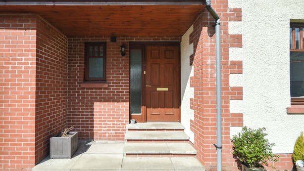 A brick house with a wooden front door, a small window, and a concrete porch. - 3 bedroom accommodation in Fort William (Fort William)