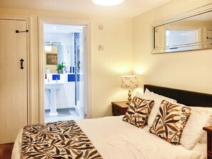 A bedroom with a bed, pillows, a nightstand, a lamp, and a mirror. - 3 bedroom accommodation in Wooton Fitzpaine, near Charmouth (Wooton Fitzpaine, near Charmouth)