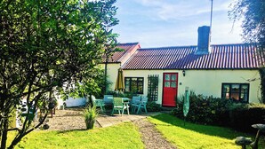 A house with a red door, a garden with a gravel path, and a table with chairs. - 3 bedroom accommodation in Wooton Fitzpaine, near Charmouth (Wooton Fitzpaine, near Charmouth)