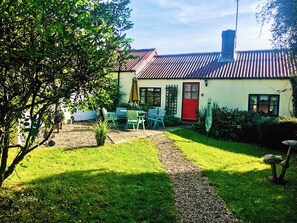A house with a red door, a garden with a gravel path, and a table with chairs. - 3 bedroom accommodation in Wooton Fitzpaine, near Charmouth (Wooton Fitzpaine, near Charmouth)