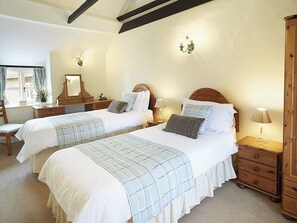 Ein Schlafzimmer mit zwei Betten, Holz-Kopfteilen, Nachttischen und einer Kommode.
