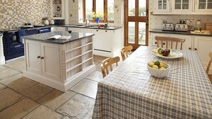 A kitchen with a central island, white cabinets, and a dining table set with a checkered tablecloth. - 5 bedroom accommodation in Wooton Fitzpaine, near Charmouth (Wooton Fitzpaine, near Charmouth)