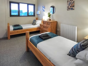 Two wooden beds with white and blue bedding, a dresser, a radiator, and a window with blinds. - A water’s edge setting in the heart of the Norfolk Broads National Park. (Brundall)