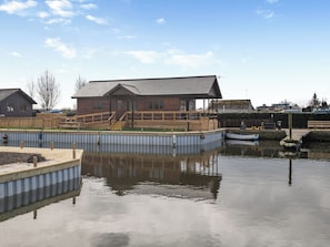 A waterfront property with a dock, a wooden building with a covered area, and a small boat. - A water’s edge setting in the heart of the Norfolk Broads National Park. (Brundall)
