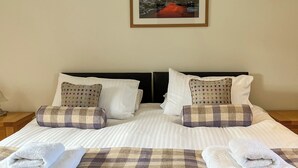 Una cama doble con dos almohadas, un edredón de cuadros y dos toallas.