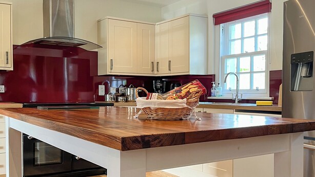 Una cocina moderna con encimeras de madera, armarios blancos y electrodomésticos de acero inoxidable.
