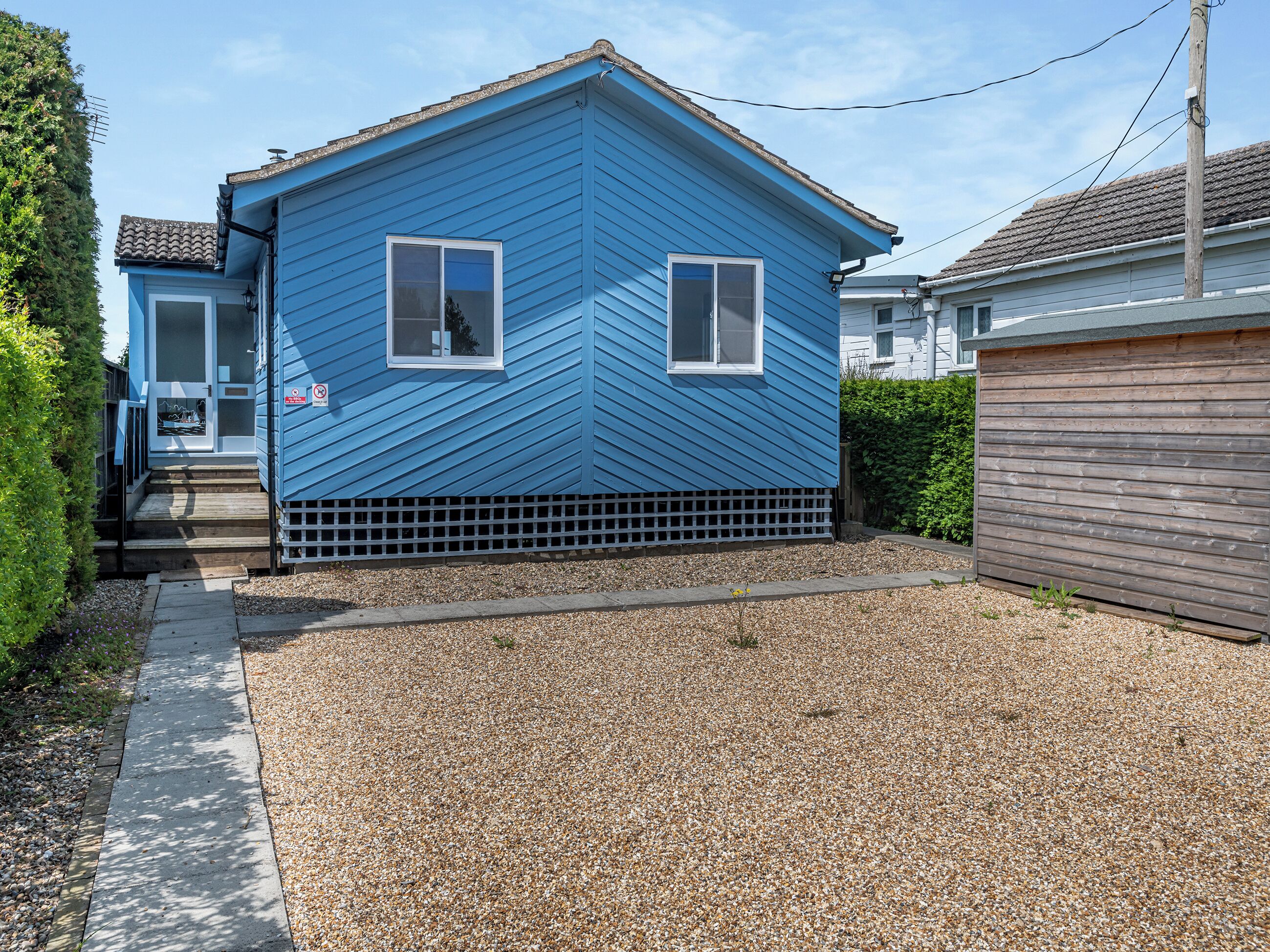 Une maison bleue avec un porche à l’avant et une allée gravillonnée.