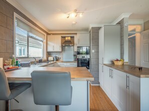 Eine moderne Küche mit Holzarbeitsplatte, weißen Schränken und einem eingebauten Backofen.