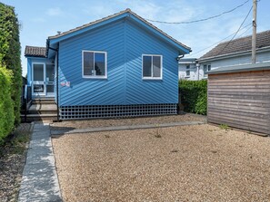 A blue house with a front porch and a gravel driveway. - A perfect waterside setting. (Brundall)
