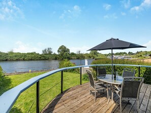 A deck with a table and chairs, overlooking a river. - A perfect waterside setting. (Brundall)