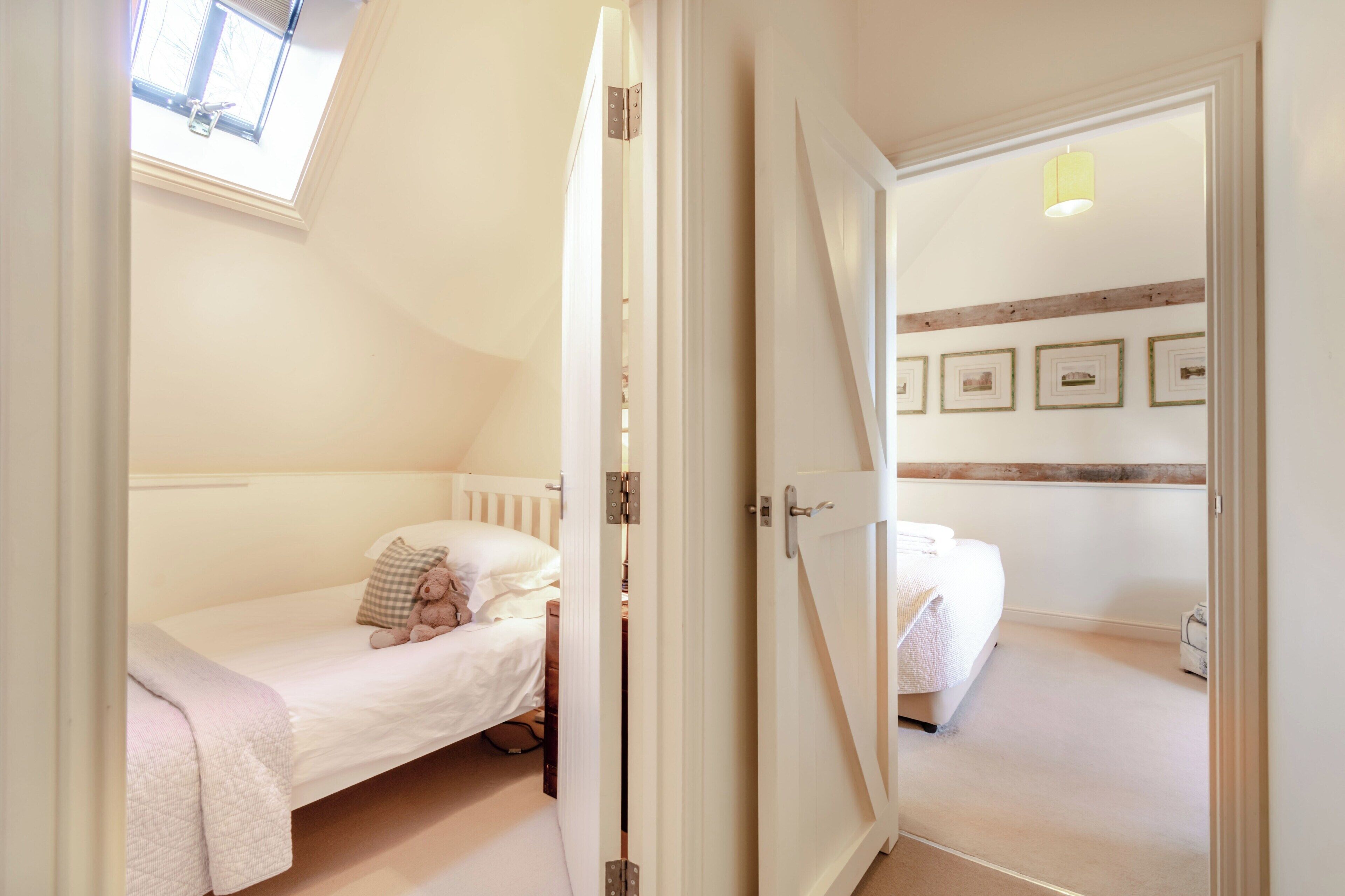 A bedroom with a single bed, a window, and a door leading to another room.