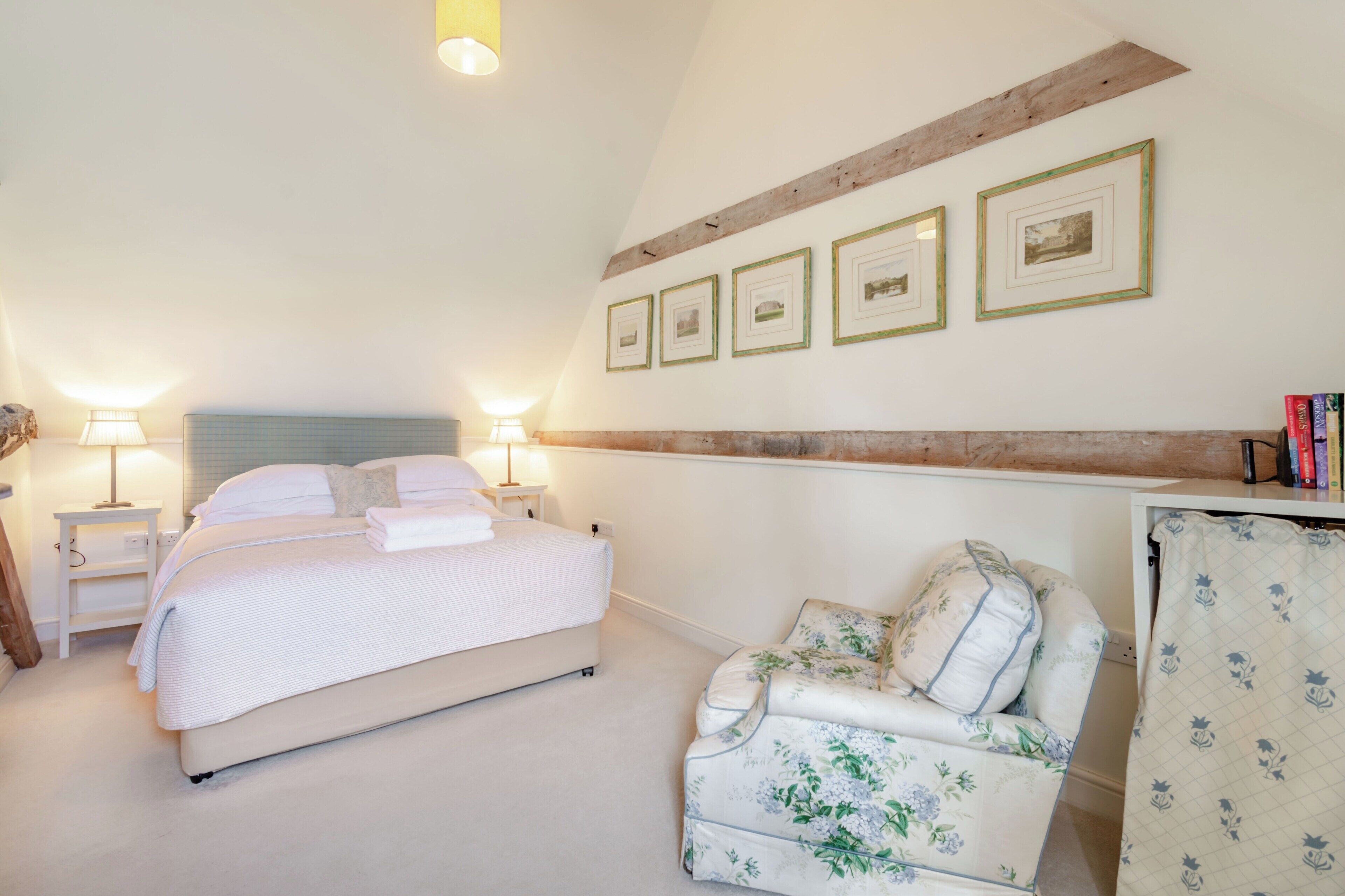 A bedroom with a bed, bedside tables, a chair, and framed pictures on the wall.