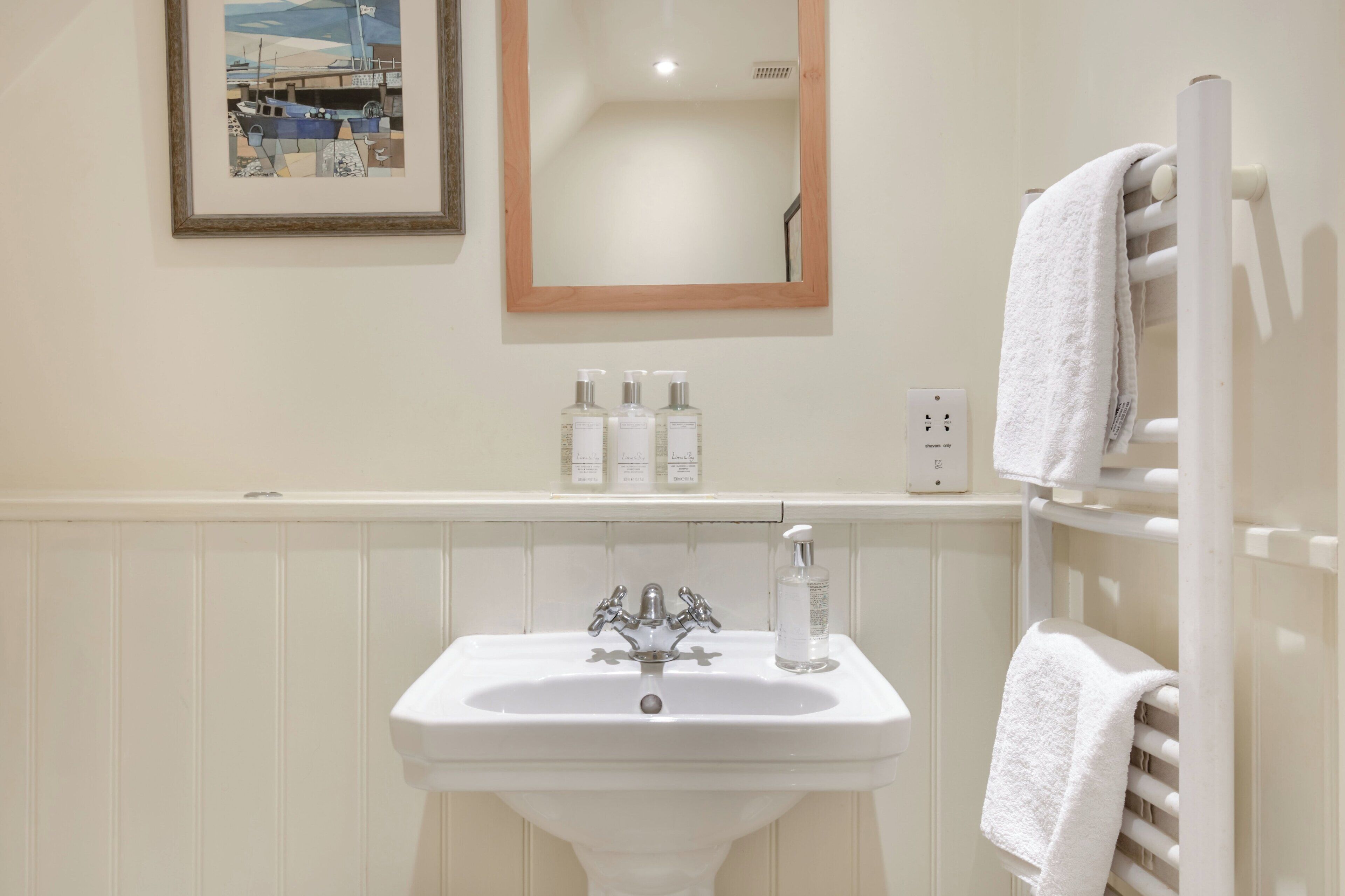 A bathroom with a white sink, a mirror, and a towel rack.