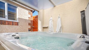 Ein Whirlpool in einem Raum mit Backsteinwand, einem Fenster mit Jalousien und einem Handtuchhalter.