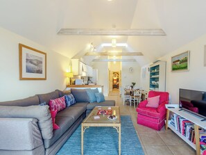 Ein modernes Wohnzimmer mit Sofa, Sessel, Couchtisch und Bücherregal.