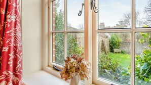 Ein Fenster mit Blick auf einen Garten, eine Bank und eine Steinmauer.