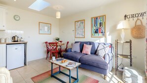 Un espacio habitable compacto con kitchenette, zona de comedor y sala de estar con sofá y mesa de centro.
