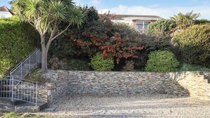 Una escalera de piedra que sube hacia una casa, con barandilla de metal.