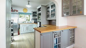 Una cocina con armarios grises, encimera de madera y vista al área de comedor.