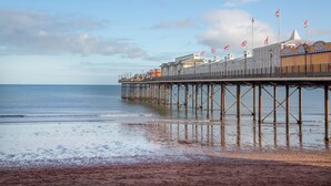 A pier extending into calm waters with a sandy beach at the end. - Mermaids View - UKC6166 (Paignton)