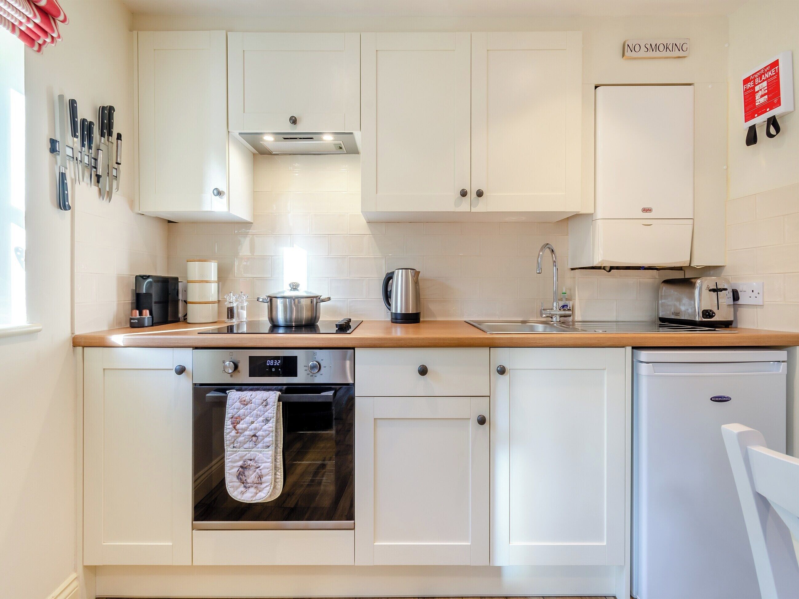 A modern kitchen with white cabinets, a stainless steel range, a built-in oven, a coffee maker, and a toaster.