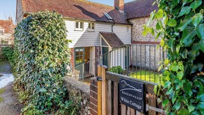 Ein traditionelles Cottage mit einer Steinmauer, einem Holztor und einem Schild, das es als Beachyhead White Cottage kennzeichnet.
