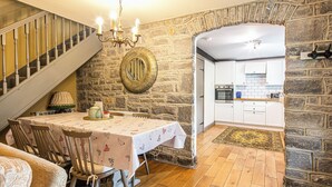 A dining area with a table set for four, a chandelier, and a stone wall. - 3 bedroom accommodation in Over Haddon, near Bakewell (Over Haddon, near Bakewell)