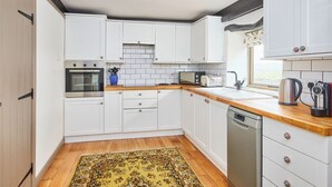 A kitchen with white cabinets, a wooden countertop, a built-in oven, a microwave, a toaster, a sink, and a dishwasher. - 3 bedroom accommodation in Over Haddon, near Bakewell (Over Haddon, near Bakewell)