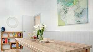 Zona pranzo con tavolo in legno, panche e una libreria piena di libri.