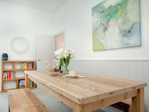 A dining area with a wooden table, bench, and a bookshelf with books. - Seagulls Rest - UKC6175 (Paignton)