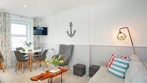Een moderne woonkamer met een bank, fauteuil, salontafel en een eethoek met stoelen en een tafel.