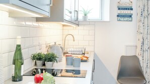 Een moderne keuken met witte kasten, een raam, een spoelbak en een stoel.