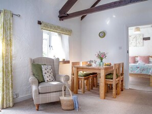 Una habitación acogedora con un sofá escocés, una mesa de comedor de madera y una cama con ropa de cama estampada.