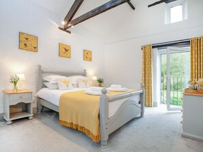 Une chambre à coucher avec un lit, des tables de chevet, une fenêtre et une vue sur l’extérieur.