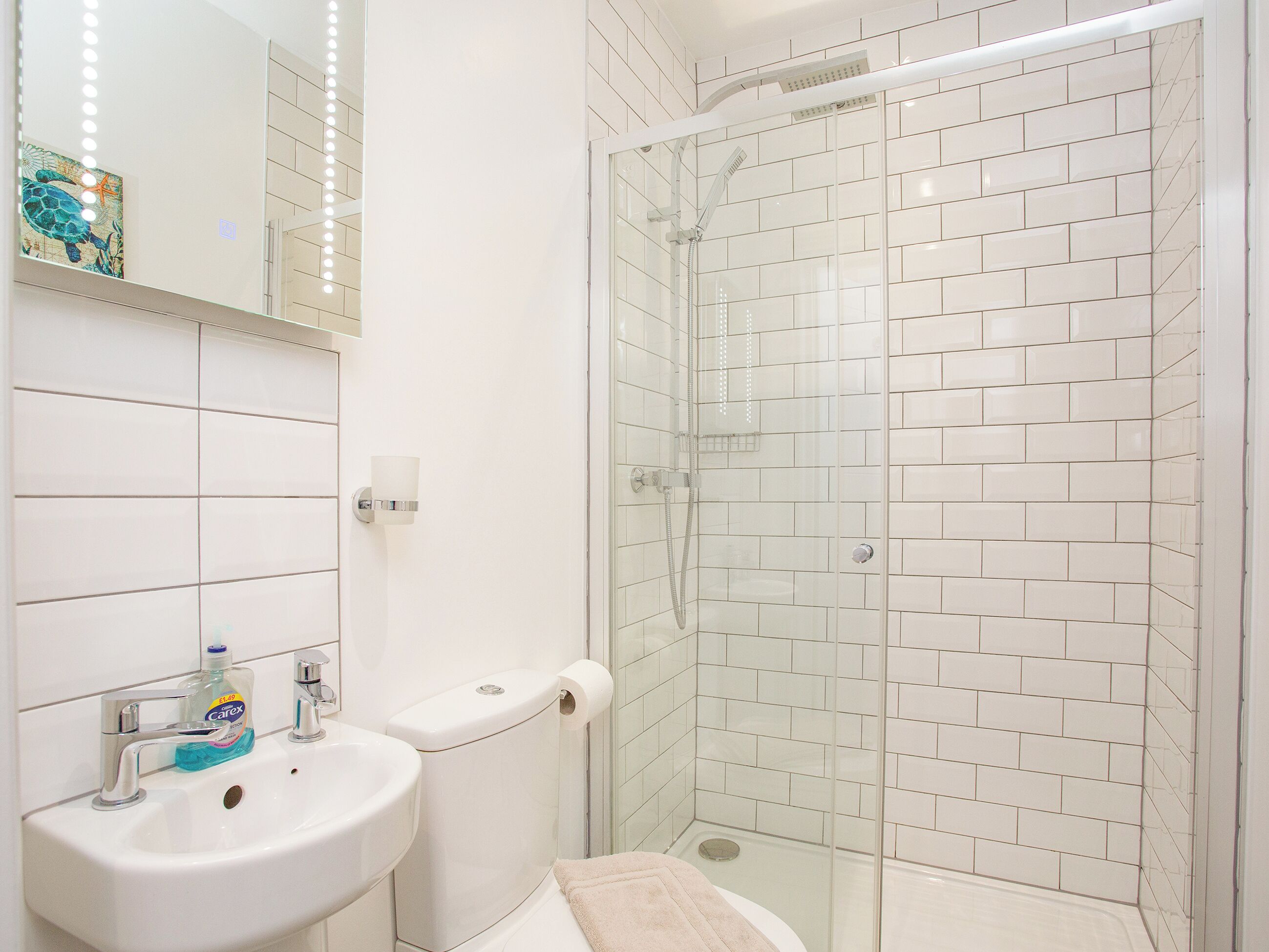 Een badkamer met een wastafel, toilet en douchecabine.