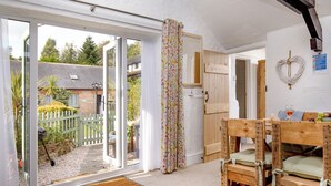 A cozy room with a wooden bed, a bench, a door leading outside, and a heart-shaped decoration on the wall. - Jasmine Cottage - UKC6179 (Marldon, near Paignton)