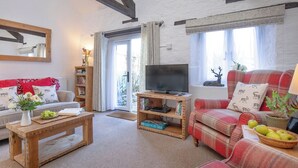 Ein Wohnzimmer mit einer Couch, einem Couchtisch, einem Fernseher und einem Bücherregal.