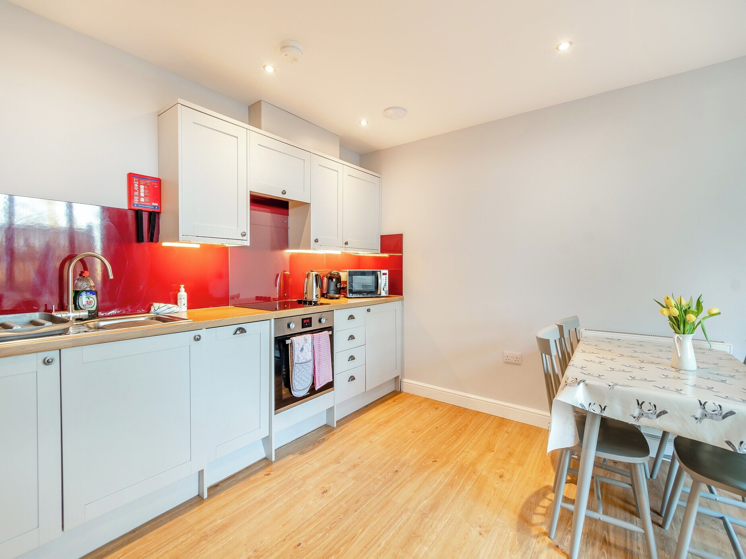 A modern kitchen with white cabinets, a wooden countertop, and a dining area with a table and chairs.