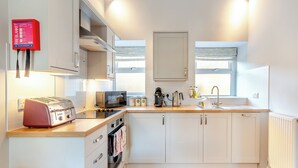 A modern kitchen with white cabinets, a built-in oven, a toaster, a kettle, and a coffee maker. - 1 bedroom accommodation in Low Hunsley, Cottingham (Low Hunsley, Cottingham)