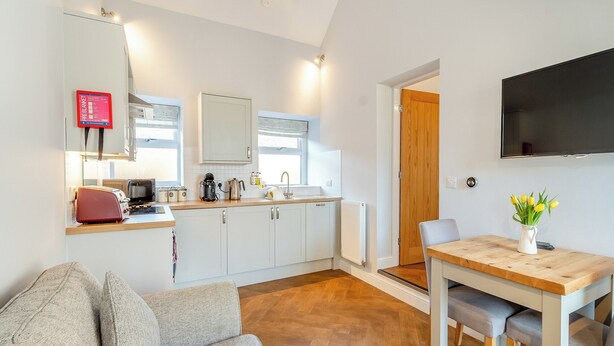 A compact kitchen with modern appliances, a dining area with a wooden table, and a cozy seating area with a sofa. - 1 bedroom accommodation in Low Hunsley, Cottingham (Low Hunsley, Cottingham)