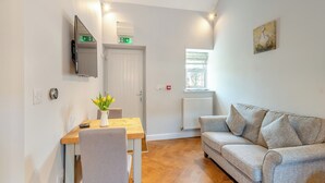 A modern living room with a wooden dining table, a grey sofa, and a painting on the wall. - 1 bedroom accommodation in Low Hunsley, Cottingham (Low Hunsley, Cottingham)