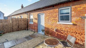 A brick house with a blue door, a small window, and a wooden fence. - 1 bedroom accommodation in Low Hunsley, Cottingham (Low Hunsley, Cottingham)